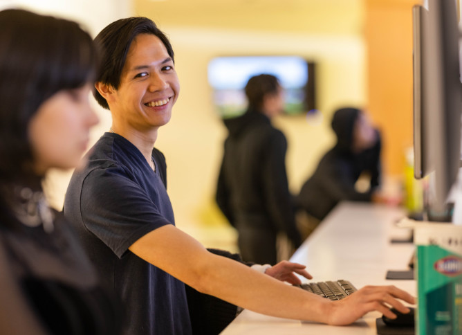 An Oakton College student smiles while using a computer.