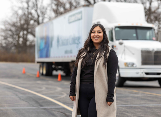 An Oakton College student stands in front of a truck.