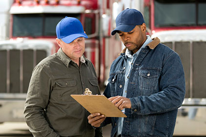 Two truck drivers standing in front of a semi.
