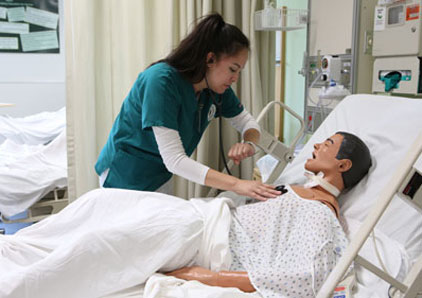 Nursing student tending to a mannequin in bed.