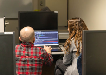 Image of instructor helping a student in the computer lab.